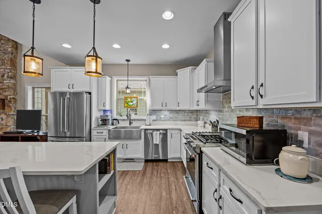 a kitchen with kitchen island granite countertop a sink a counter space appliances and cabinets