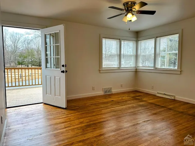 a view of an empty room with a window and wooden floor