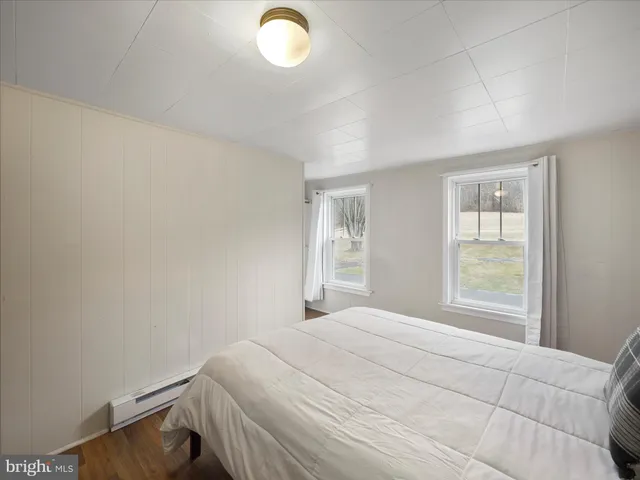 a bedroom with a bed and a dresser next to a window