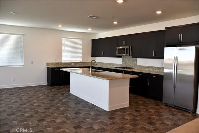 a kitchen with kitchen island stainless steel appliances a sink stove and refrigerator