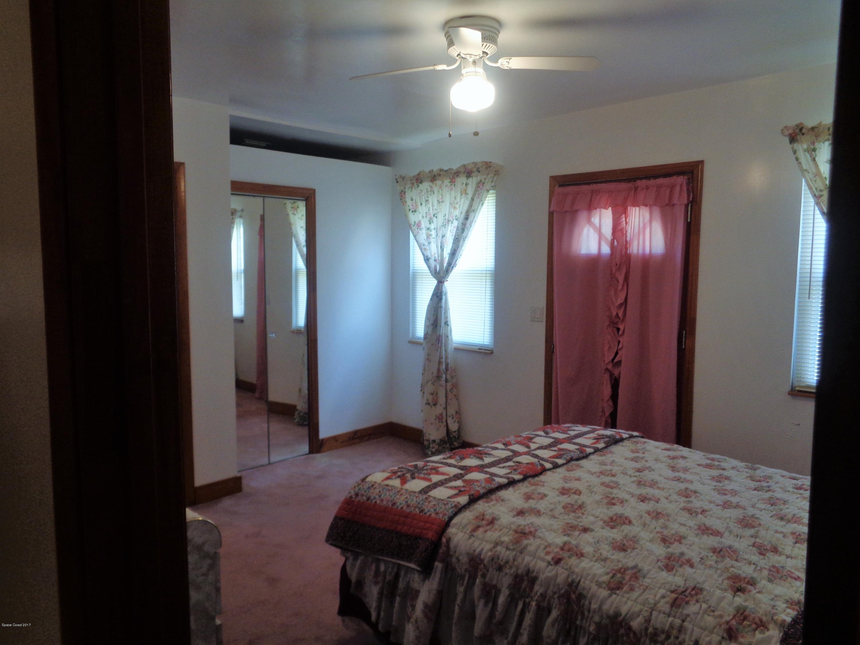 3630 Hield Road West Melbourne, FL 32904 - Photo 14 of 27 a bedroom with a large bed and a chandelier