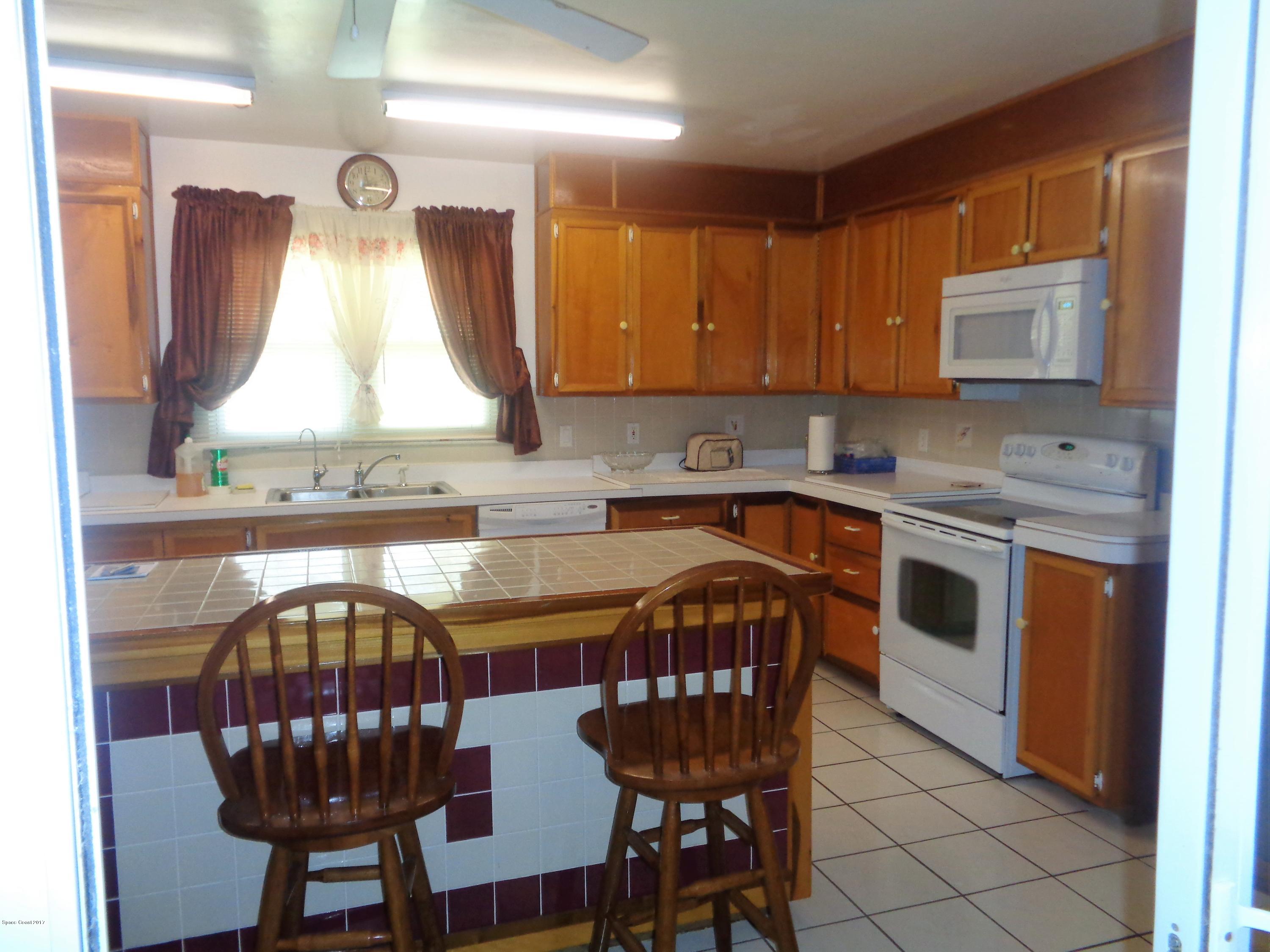 3630 Hield Road West Melbourne, FL 32904 - Photo 8 of 27 a kitchen with stainless steel appliances granite countertop a stove a sink dishwasher a microwave oven with a dining table and chairs