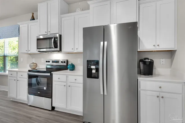 a kitchen with stainless steel appliances white cabinets and a refrigerator