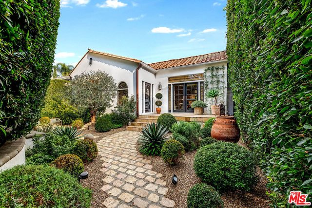 a view of a house with potted plants and a large tree