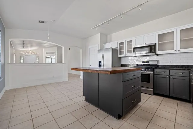 a kitchen with stainless steel appliances granite countertop white cabinets and a stove top oven