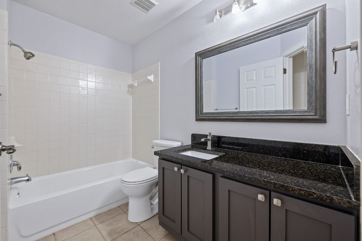 9324 Muskberry Cove Austin, TX 78717 - Photo 22 of 26 a bathroom with a granite countertop sink a toilet a bathtub and a shower