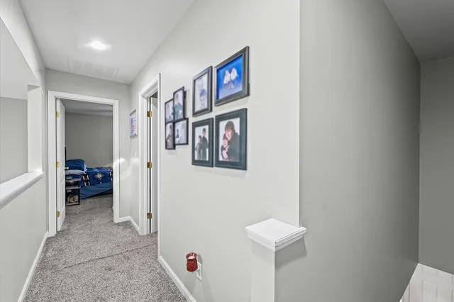 a view of a hallway with bed and a refrigerator