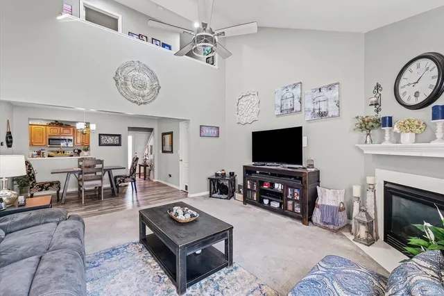 a living room with furniture a clock on wall and a flat screen tv