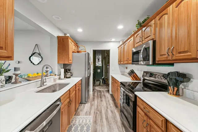 a kitchen with kitchen island granite countertop a sink a stove top oven a refrigerator with wooden cabinets and floor