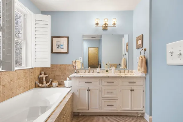 a bathroom with a bathtub a double vanity sink and mirror