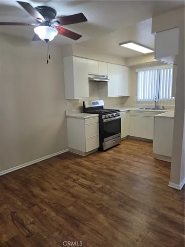 a kitchen with stainless steel appliances granite countertop a sink cabinets and wooden floor