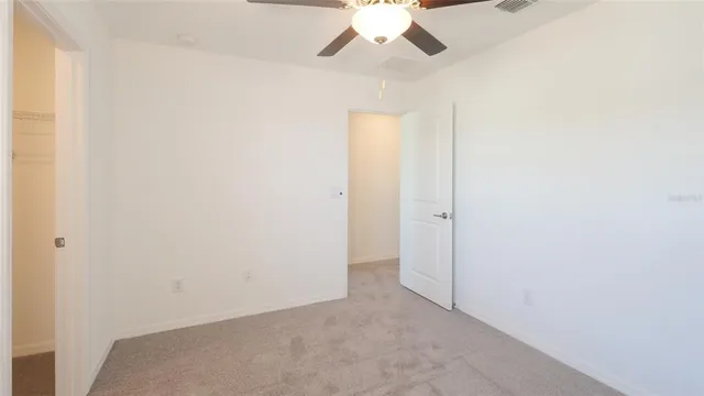 an empty room with a ceiling fan and window