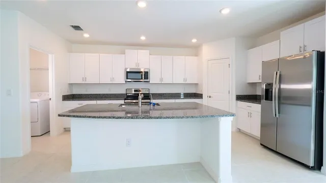 a kitchen with stainless steel appliances granite countertop a sink a refrigerator and a stove