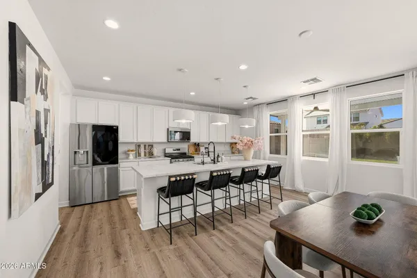 a living room with stainless steel appliances furniture wooden floor and a kitchen view
