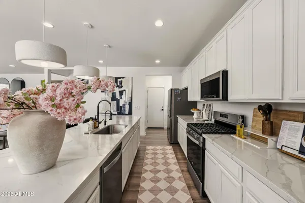 a living room with stainless steel appliances furniture wooden floor and a kitchen view