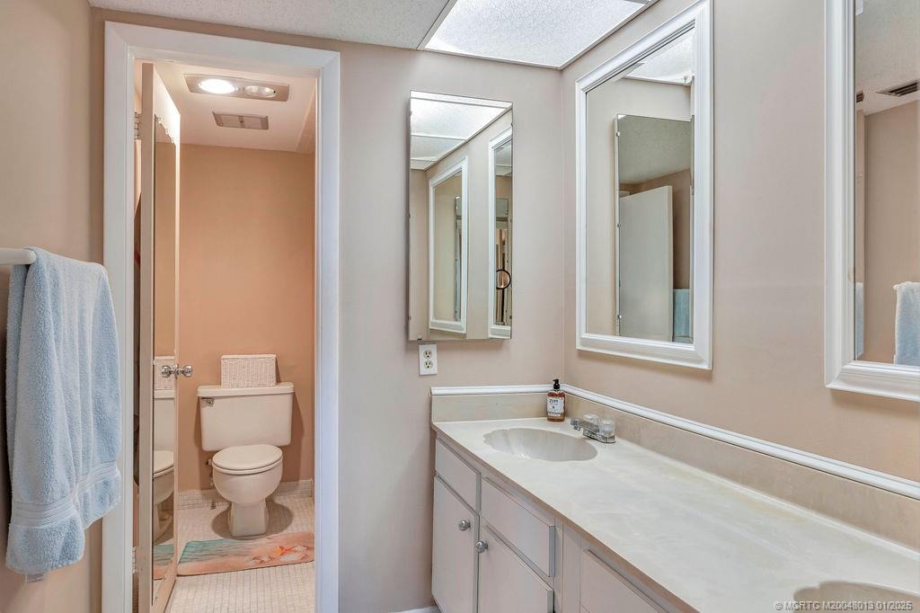 3901 Southeast St Lucie Boulevard, Unit 75 Stuart, FL 34997 - Photo 27 of 48 a bathroom with a granite countertop sink a toilet and a mirror