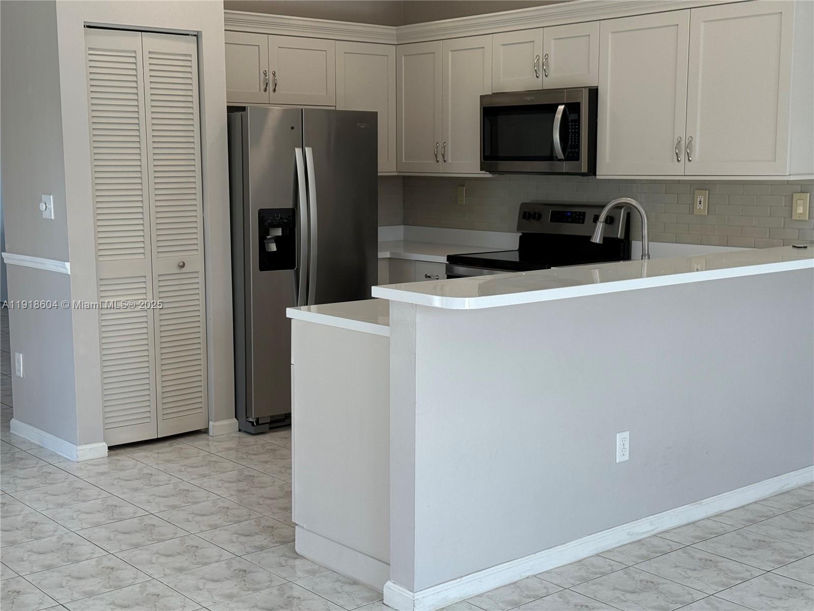17449 Southwest 143rd Place Miami, FL 33177 - Photo 3 of 19 a view of a kitchen with refrigerator and cabinets