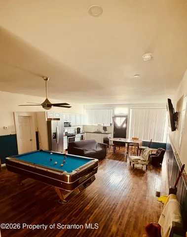 a living room with furniture pool table and a wooden floor