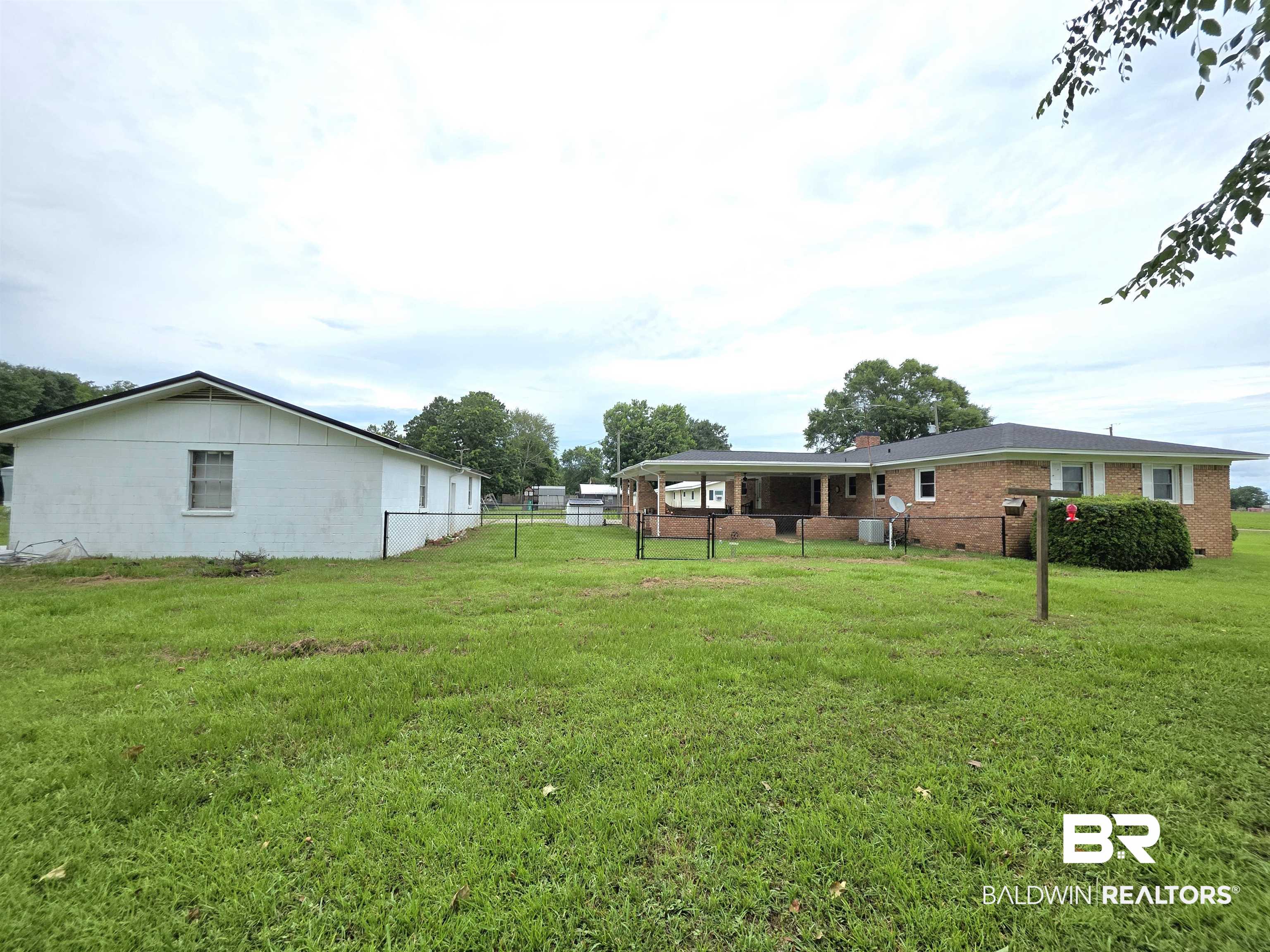 558 Stanton Road Atmore, AL 36502 - Photo 22 of 29 Expansive grassy yard featuring a brick-clad residence with a covered patio, and a separate white outbuilding