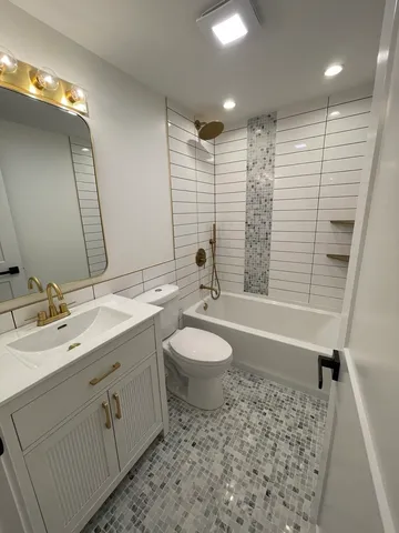 a bathroom with a toilet a sink a mirror a bathtub and vanity