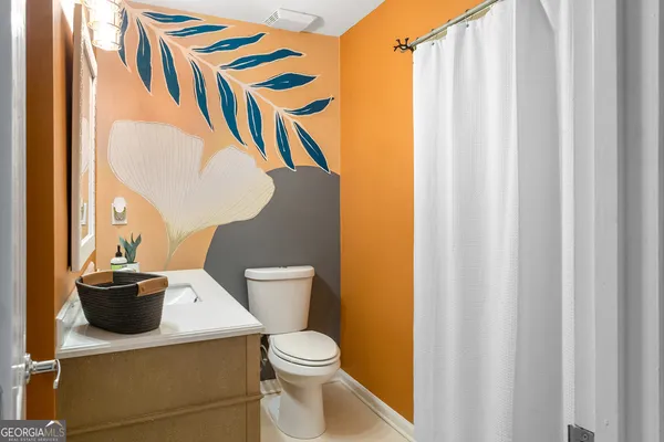 a bathroom with a granite countertop sink and a toilet