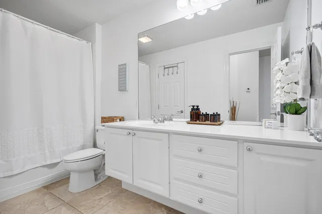 a spacious bathroom with a double vanity sink toilet and a mirror