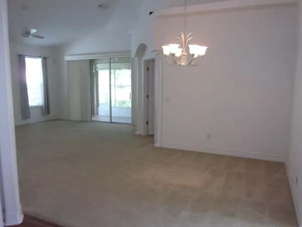 a view of a big room with windows and chandelier fan