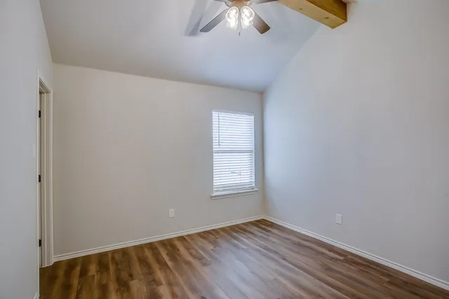 a view of an empty room with chandelier fan and wooden floor