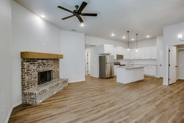 a view of kitchen with kitchen island wooden floor center island and stainless steel appliances