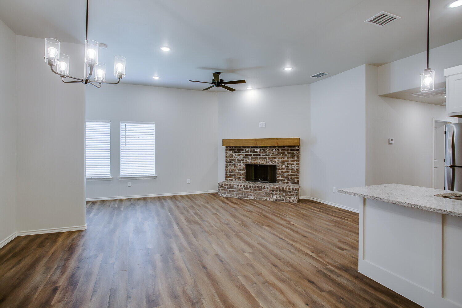 12106 Elkhart Avenue, Unit B Lubbock, TX 79424 - Photo 5 of 17 an empty room with wooden floor fireplace and chandelier