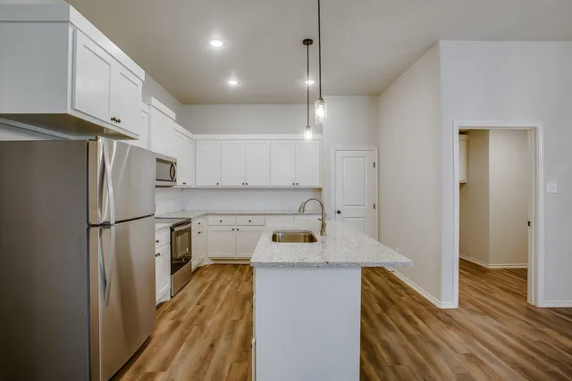 a kitchen with a refrigerator a sink and wooden floor