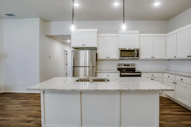 a kitchen with stainless steel appliances a sink a stove a refrigerator and cabinets