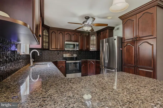 a kitchen with stainless steel appliances granite countertop a refrigerator a stove a sink and a granite counter tops