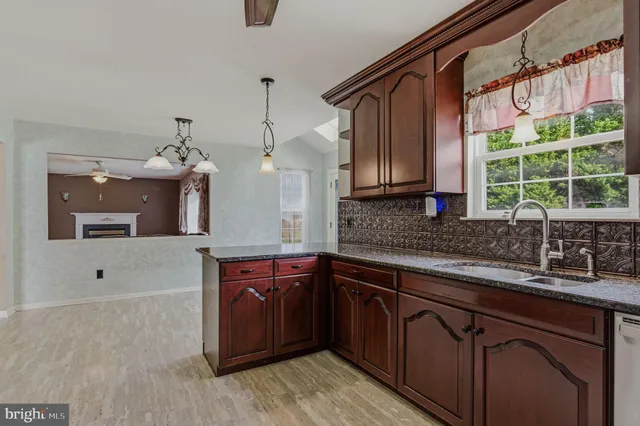 a kitchen with stainless steel appliances granite countertop a sink a stove and a wooden cabinets