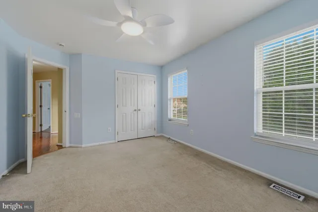 an empty room with windows and fan