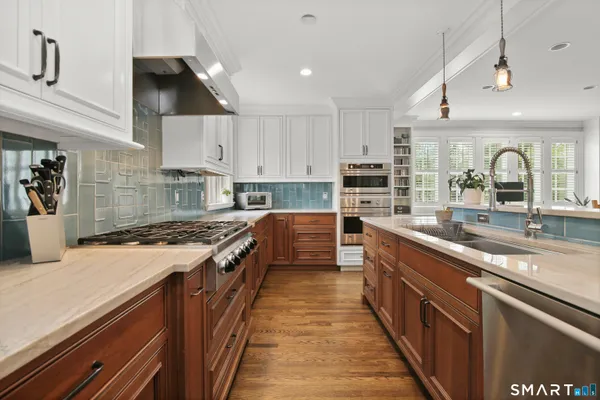 a large kitchen with stainless steel appliances granite countertop a lot of counter space and wooden floor