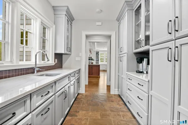 a large white kitchen with granite countertop a sink and dishwasher next to a large window