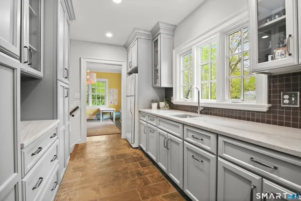 a large white kitchen with granite countertop a large window and a sink