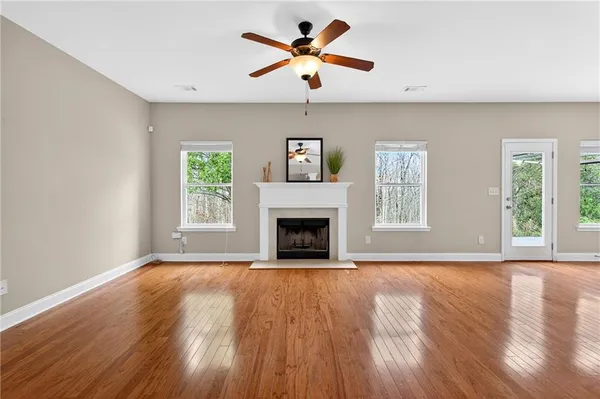a view of a livingroom with a fireplace a ceiling fan and a hardwood floor