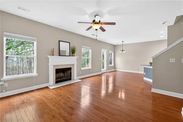 a view of an empty room with wooden floor fireplace and a window