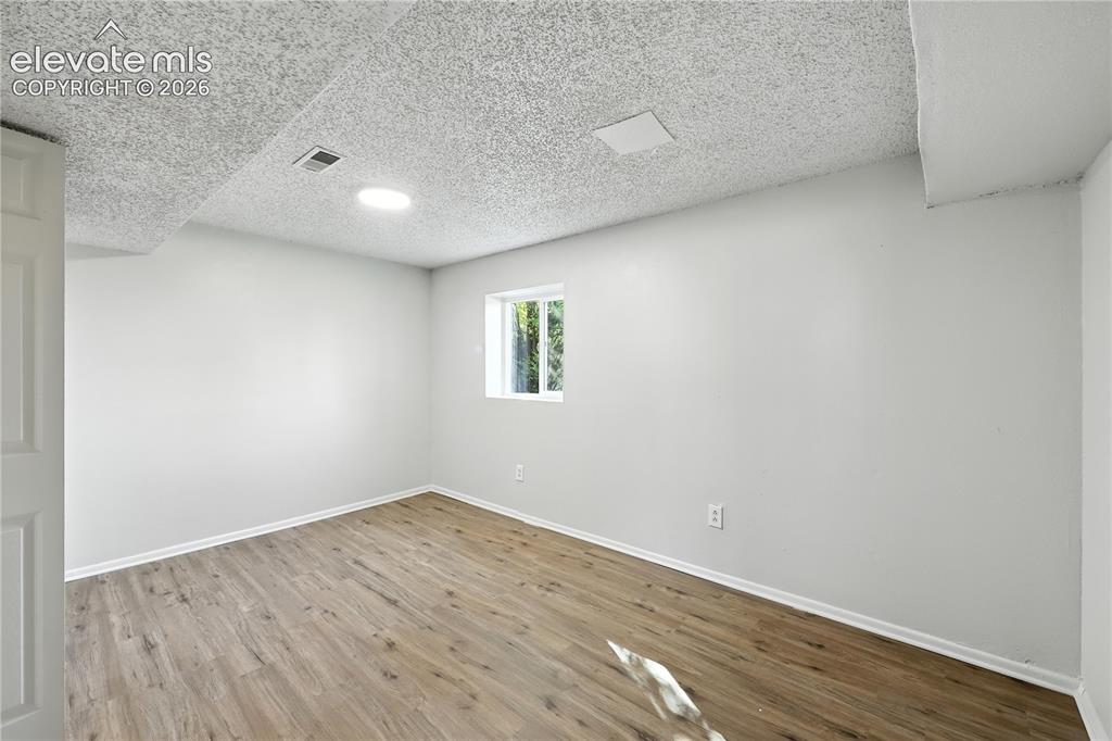 7033 Sequoyah Way Colorado Springs, CO 80915 - Photo 10 of 20 an empty room with wooden floor and windows