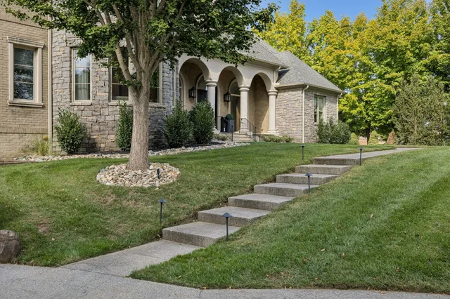 a front view of a house with garden and trees