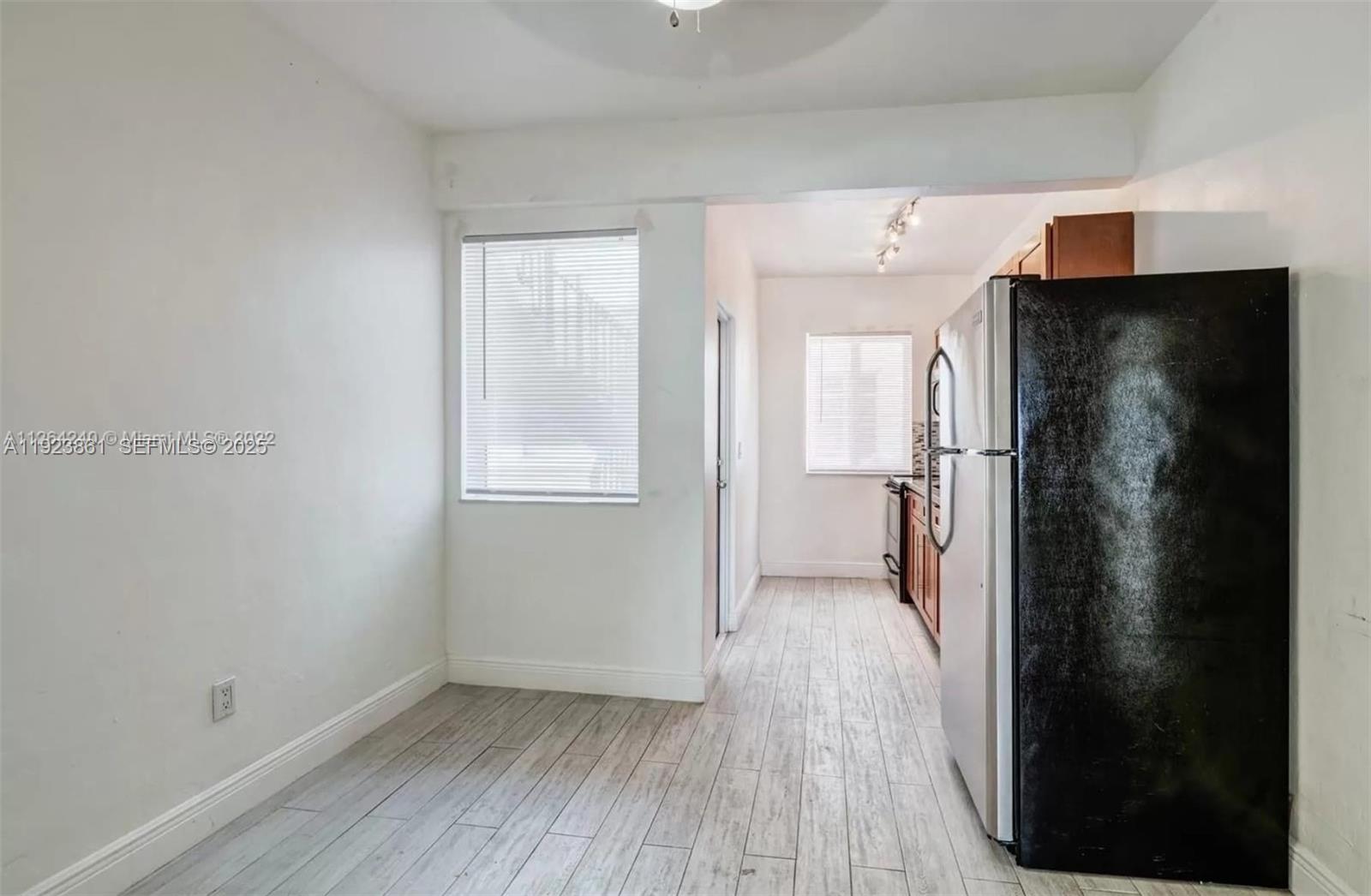 610 12th Street, Unit 5 Miami Beach, FL 33139 - Photo 4 of 8 a view of a refrigerator in kitchen and an empty room with wooden floor windows