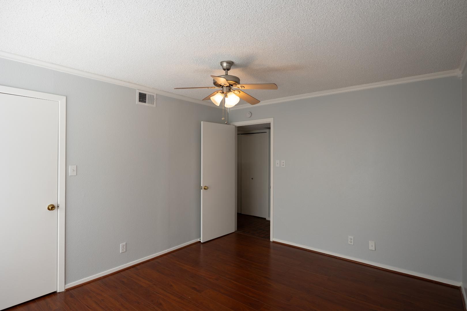 2110 Rio Grande Street, Unit 307 Austin, TX 78705 - Photo 9 of 12 Warm hardwood floors and a ceiling fan create a comfortable and inviting atmosphere in this chamber.