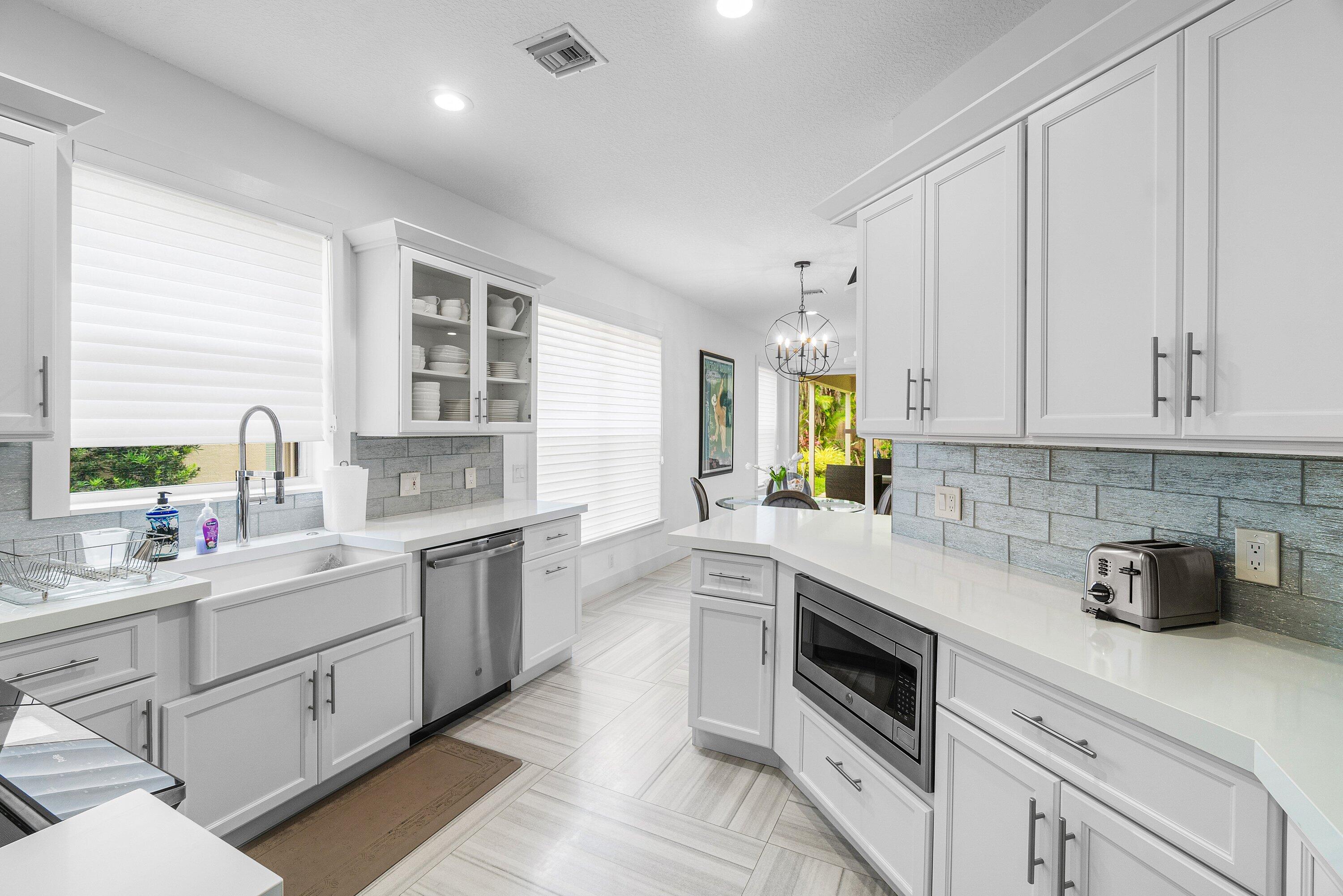2404 Northwest 67th Street Boca Raton, FL 33496 - Photo 11 of 74 a kitchen with a sink dishwasher and white cabinets with wooden floor