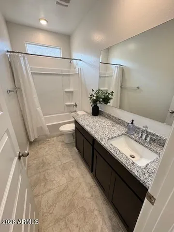 a bathroom with a granite countertop sink a toilet and shower