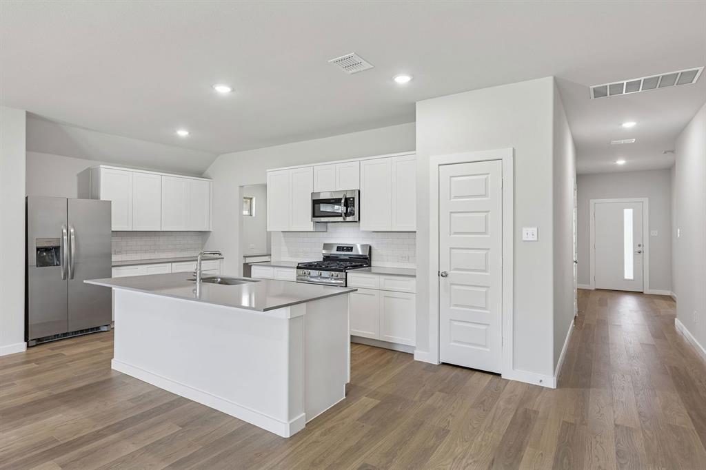 671 Sierra Ridge Lavon, TX 75166 - Photo 4 of 33 a large kitchen with stainless steel appliances a refrigerator and a stove top oven