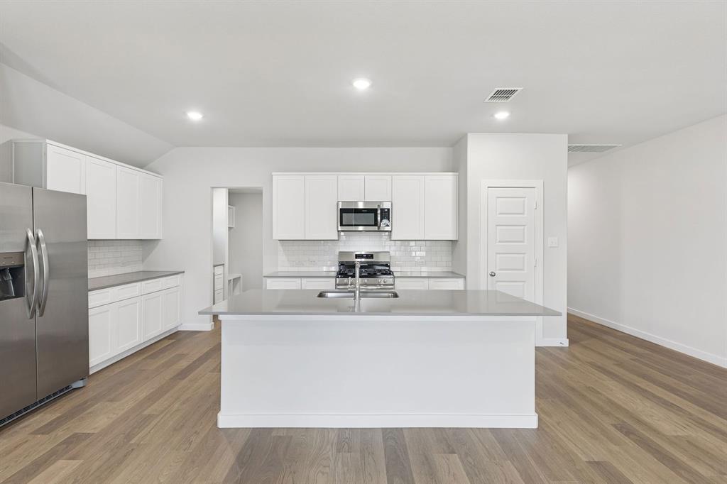 671 Sierra Ridge Lavon, TX 75166 - Photo 5 of 33 a large kitchen with stainless steel appliances a large counter top a stove and a refrigerator