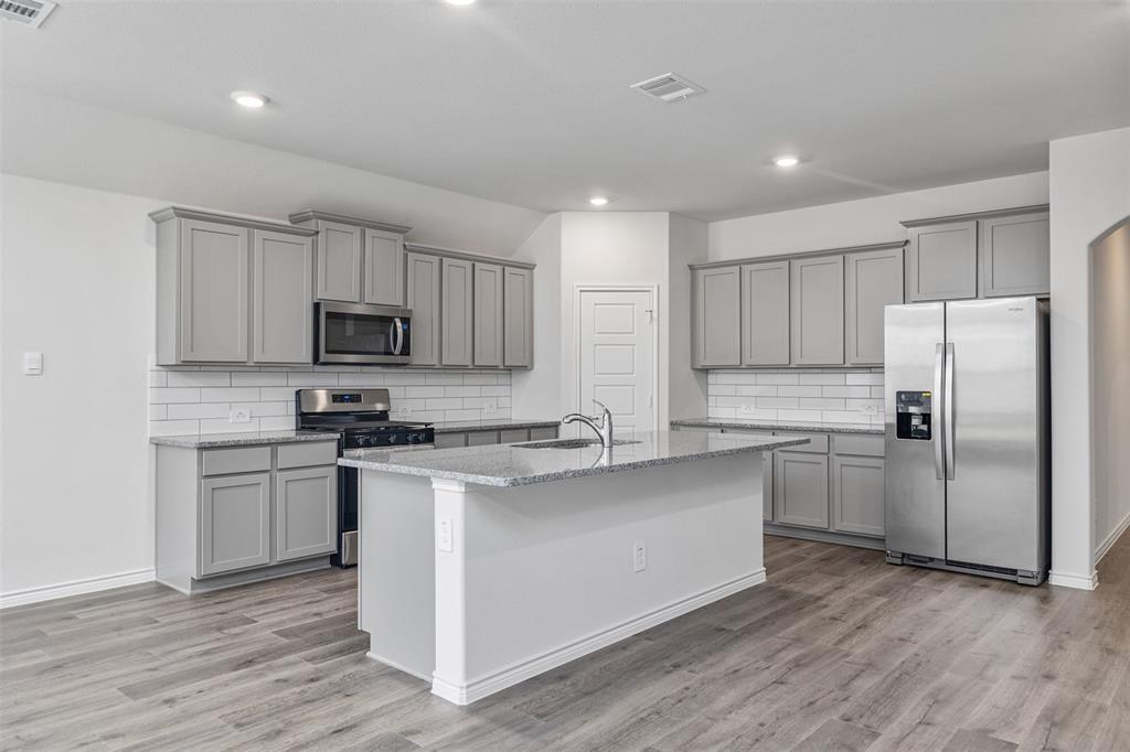 10305 Rambling Brks Lane Aubrey, TX 76227 - Photo 11 of 28 a kitchen with stainless steel appliances a refrigerator sink and microwave