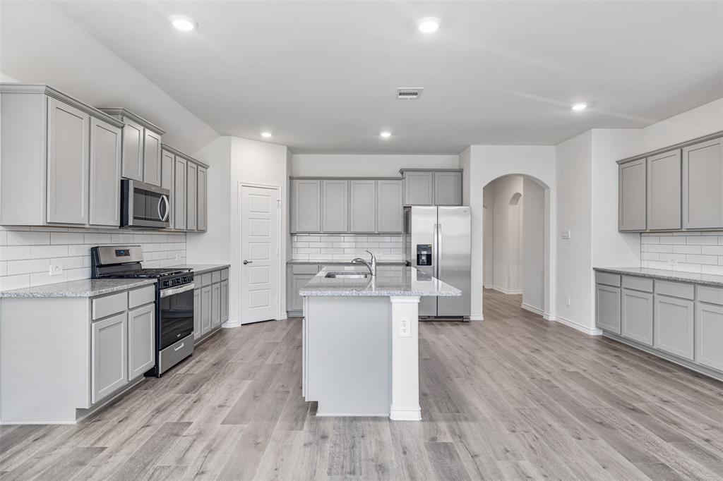 10305 Rambling Brks Lane Aubrey, TX 76227 - Photo 12 of 28 a kitchen with stainless steel appliances a microwave a stove a sink dishwasher a refrigerator and white cabinets with wooden floor